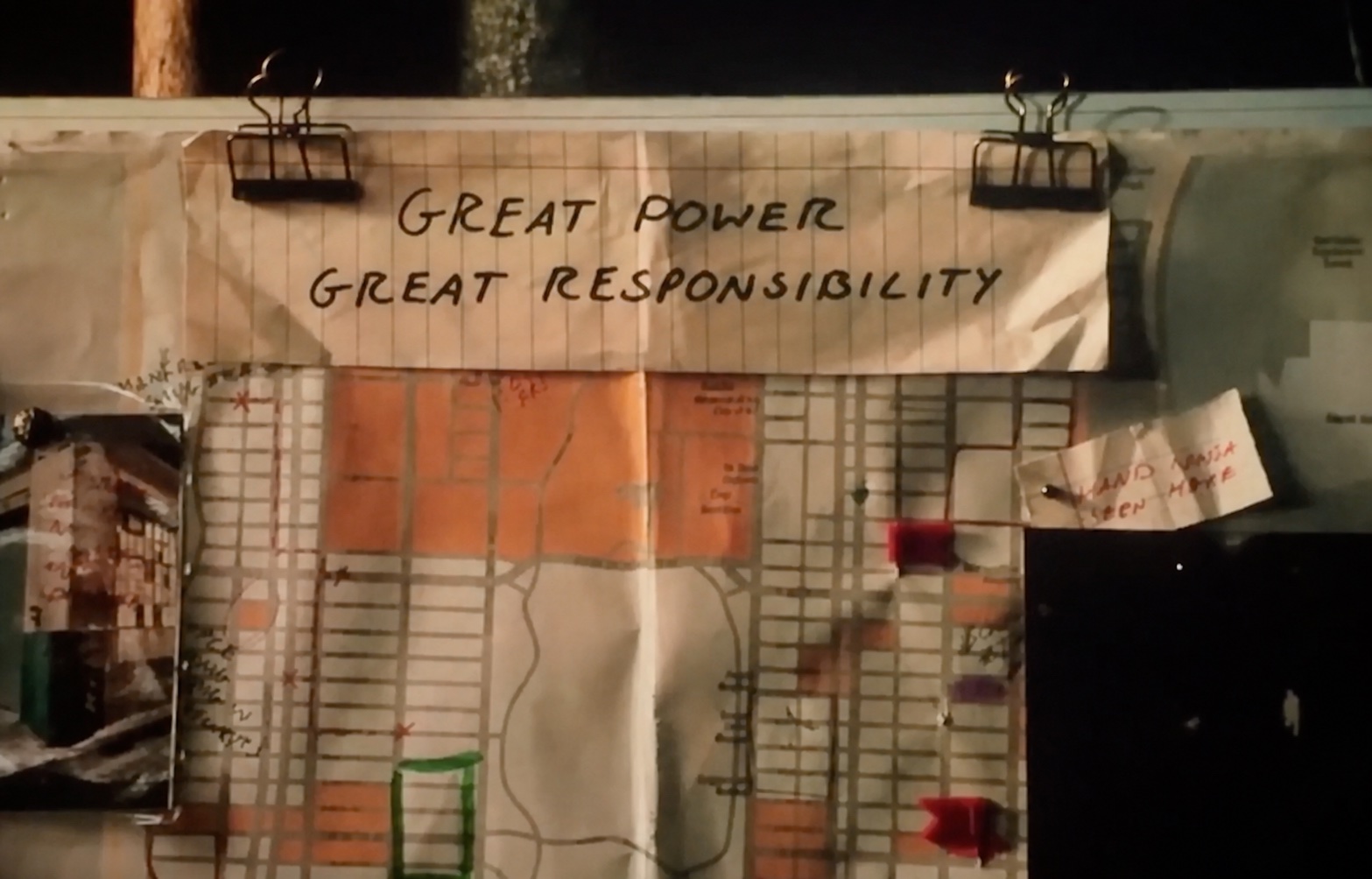 Handwritten note reading Great Power Great Responsibility pinned above a city map